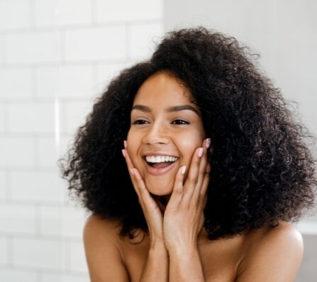Photo of a happy woman with great skin looking in the mirror after a shower